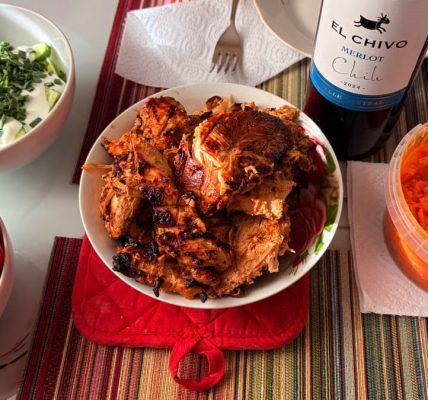 A vibrant dinner setup featuring grilled chicken, fresh tomatoes, and Merlot wine, perfect for gatherings.