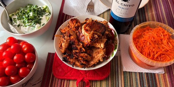 A vibrant dinner setup featuring grilled chicken, fresh tomatoes, and Merlot wine, perfect for gatherings.